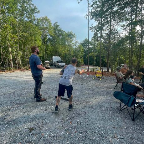 men playing a lawn game outdoors in wooded campground scene