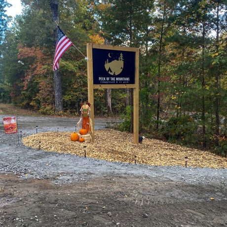 Peek of the Mountains RV Park signage in wooded setting